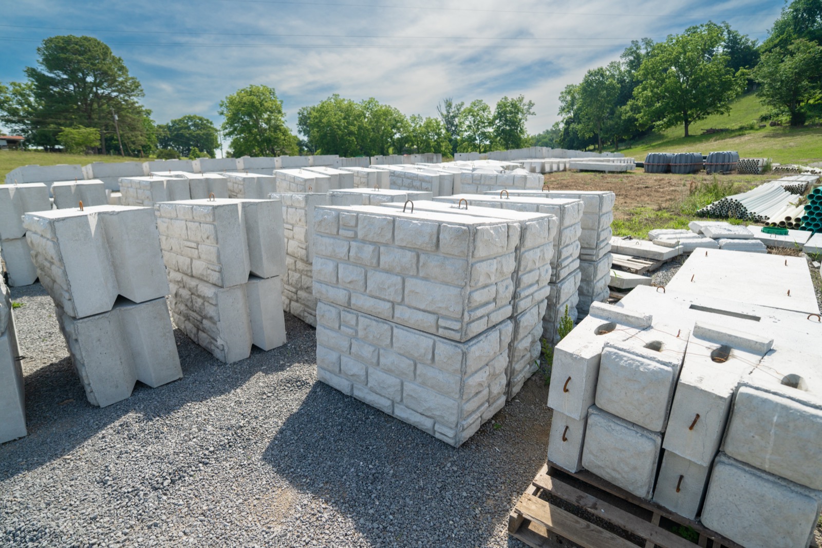 Pallets of precast concrete retaining wall blocks in textured and smooth finishes at the Daniels Septic and Precast yard