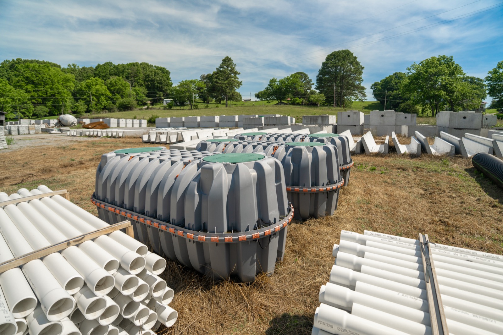 Plastic septic tanks staged alongside PVC pipe and concrete tanks at the Daniels Septic and Precast yard, Tazewell, TN