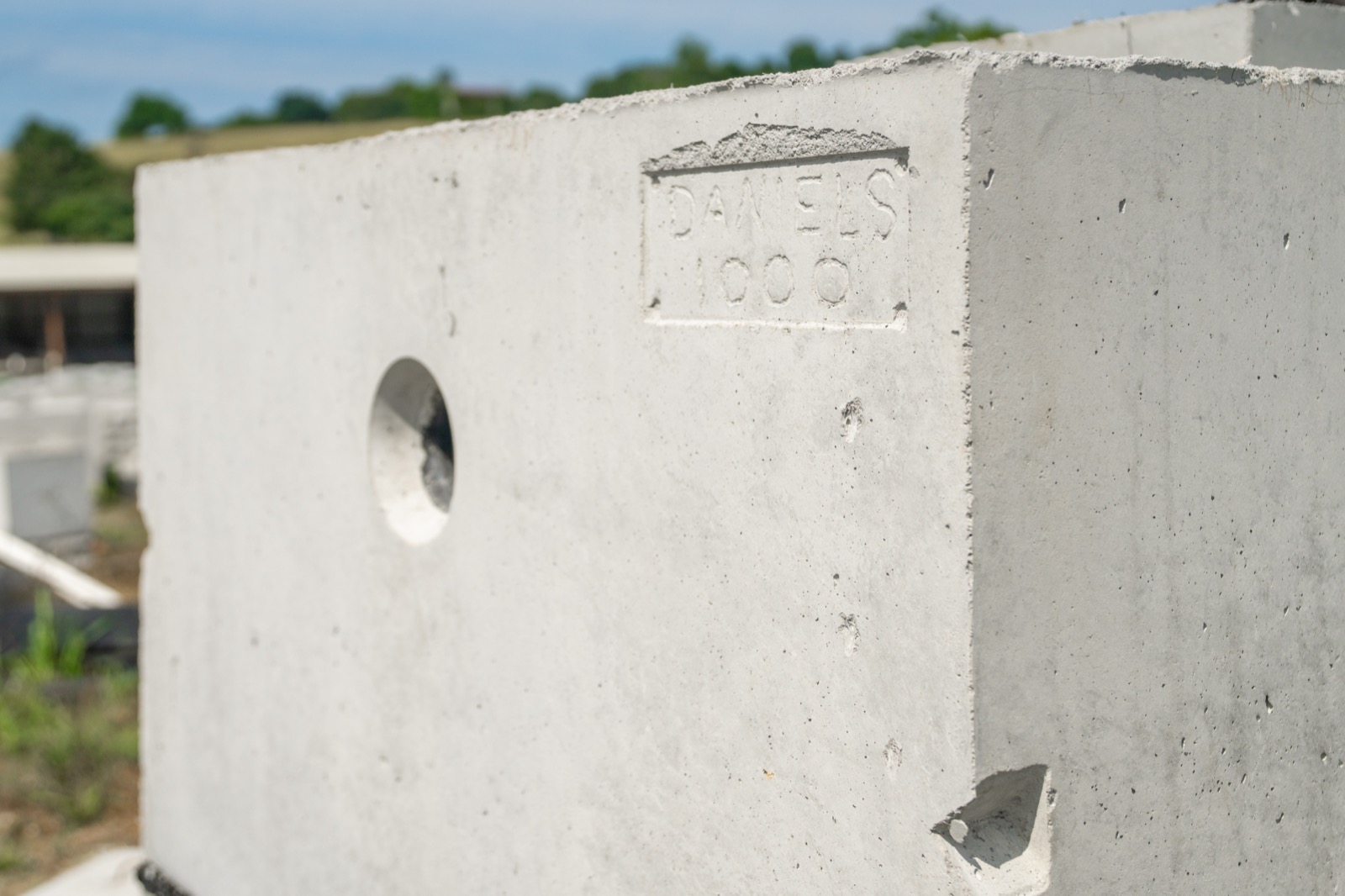 Close-up of a precast concrete septic tank stamped DANIELS 1000 with inlet hole visible